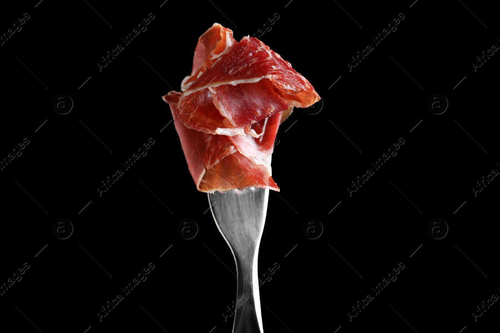 Photo of Tasty prosciutto on fork against black background