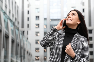 Photo of Beautiful woman in stylish suit talking on phone outdoors. Space for text