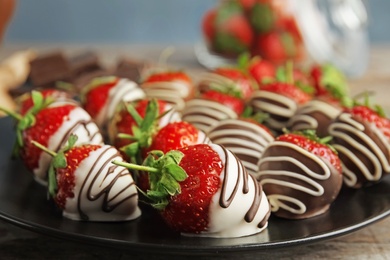 Photo of Plate with chocolate covered strawberries on table, closeup