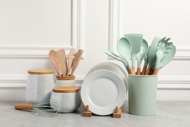 Set of different kitchenware on light gray table near white wall
