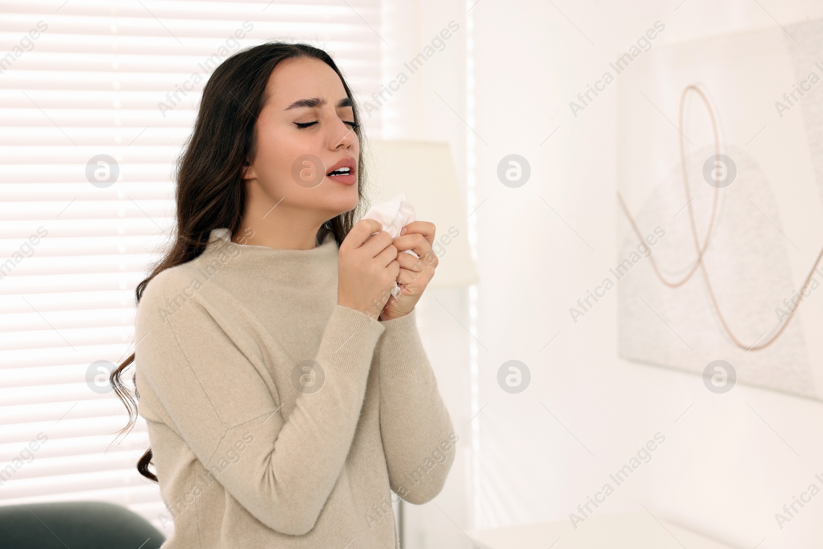 Photo of Sick woman with tissue sneezing at home, space for text. Cold symptoms