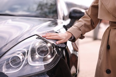 Photo of Woman wiping her modern car with rag, closeup