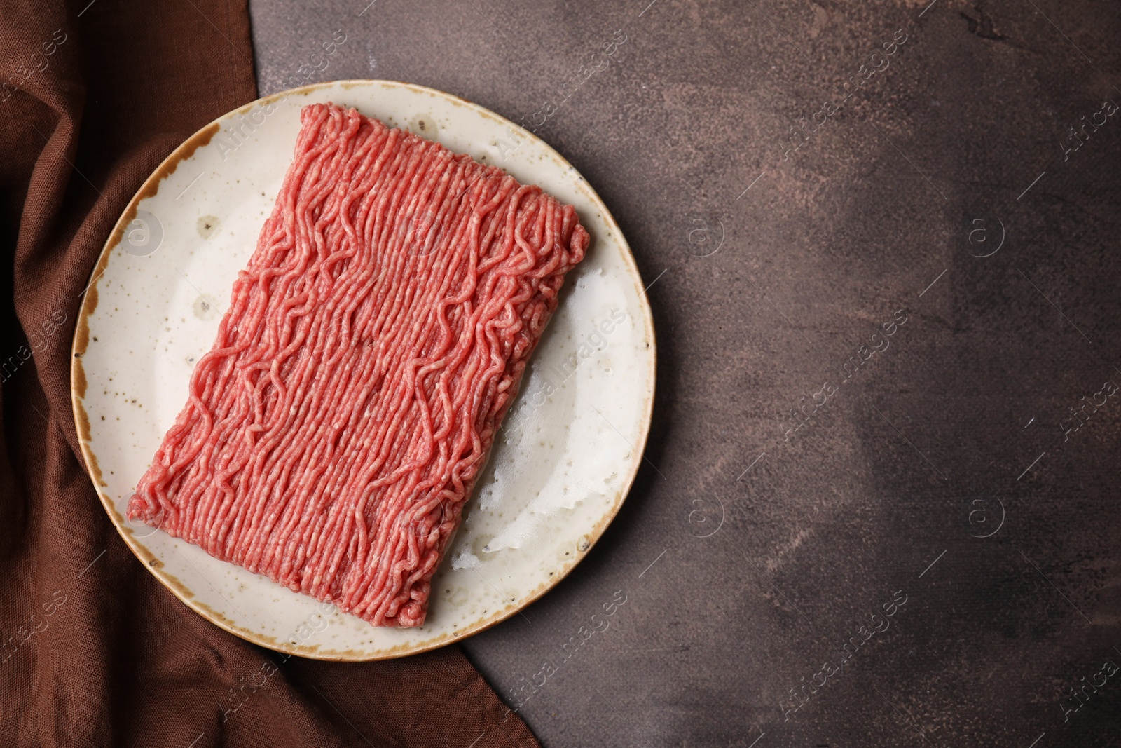 Photo of Fresh raw ground meat on brown textured table, top view. Space for text