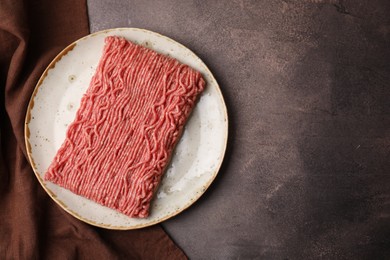 Photo of Fresh raw ground meat on brown textured table, top view. Space for text