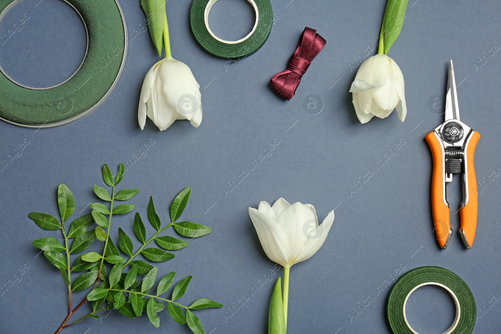 Photo of Florist equipment with flowers on color background, top view