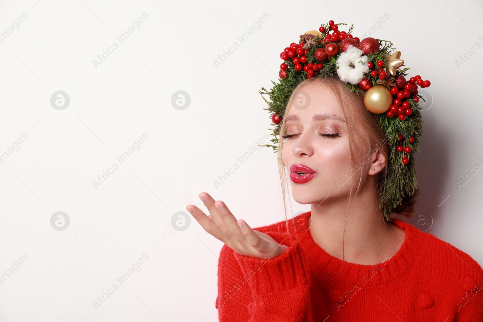 Photo of Beautiful young woman wearing Christmas wreath on white background. Space for text