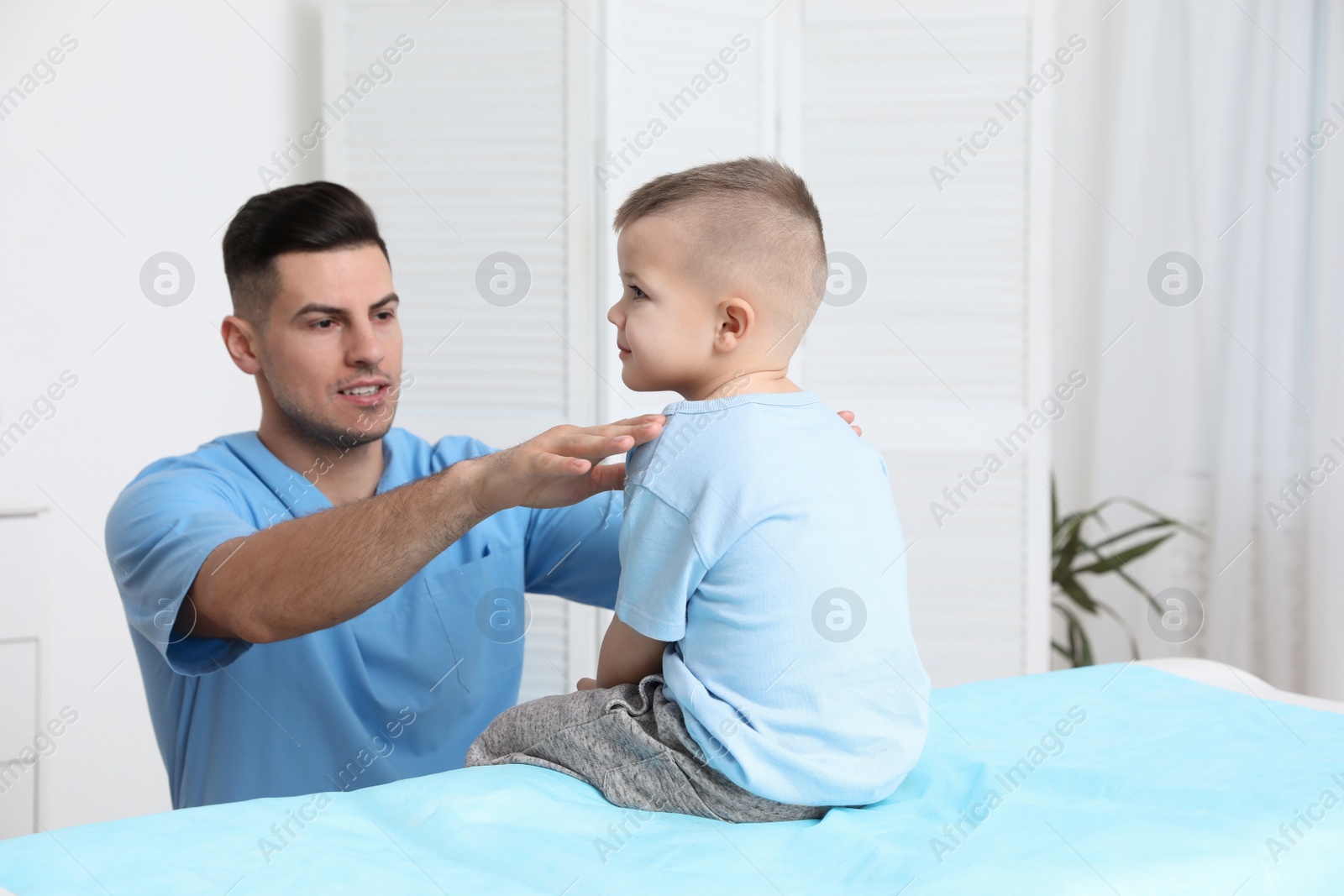 Photo of Orthopedist examining child's back in clinic. Scoliosis treatment