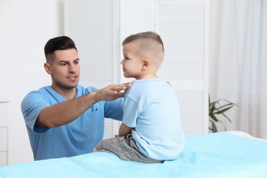 Photo of Orthopedist examining child's back in clinic. Scoliosis treatment