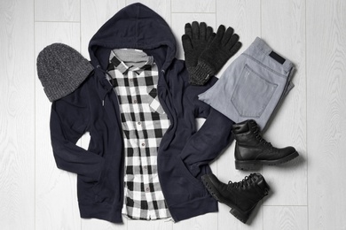 Flat lay composition with winter clothes and boots on white wooden background