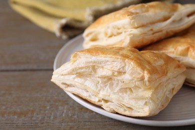 Photo of Delicious fresh puff pastries on wooden table, closeup. Space for text