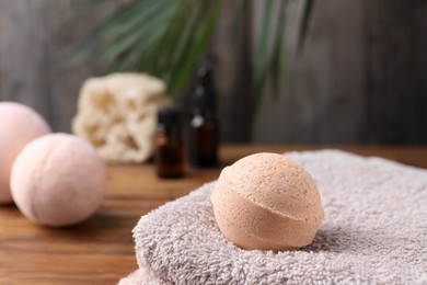 Photo of Beautiful aromatic bath bomb and towel on wooden table, closeup. Space for text