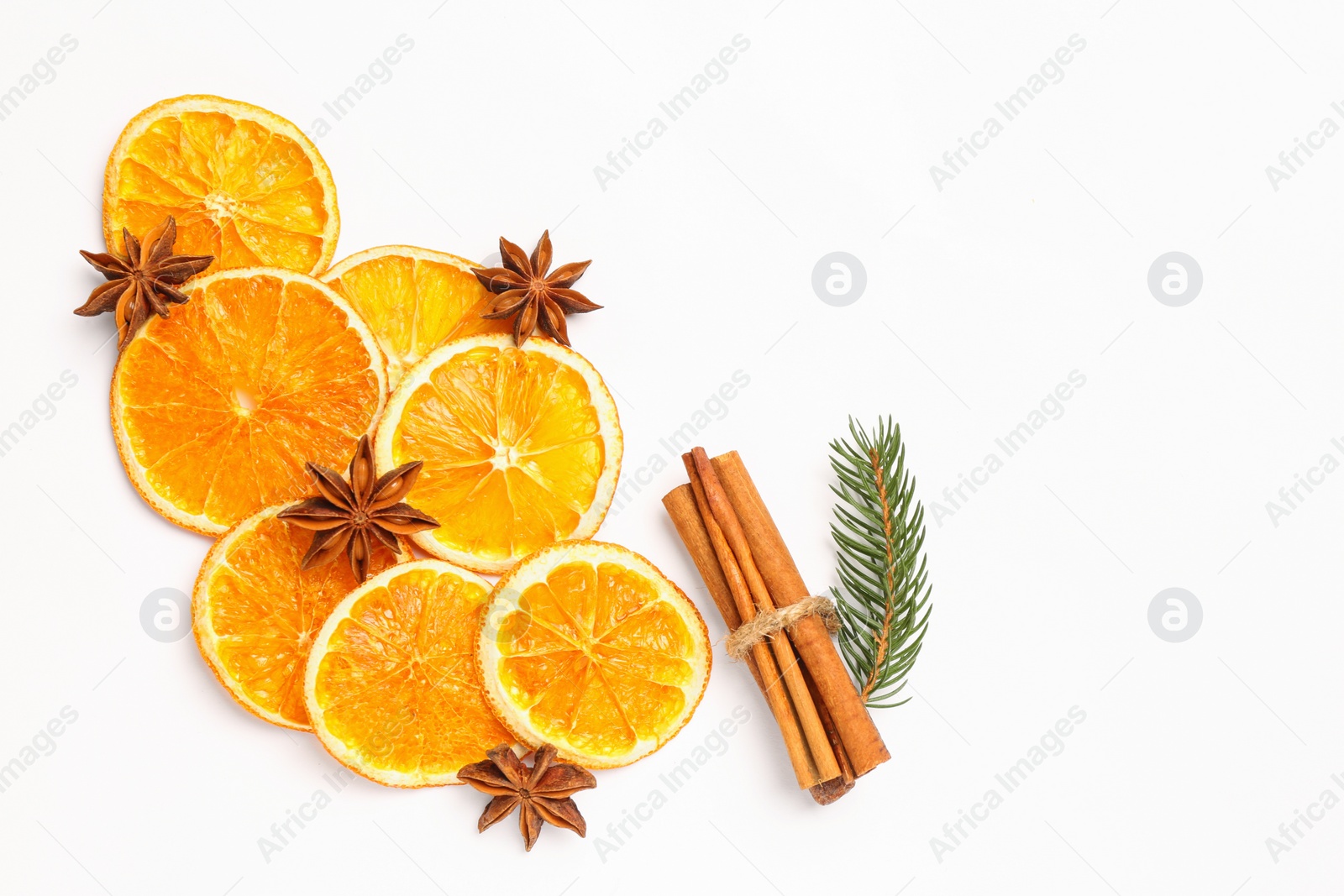 Photo of Dry orange slices, fir branch, cinnamon sticks and anise stars on white background, flat lay. Space for text