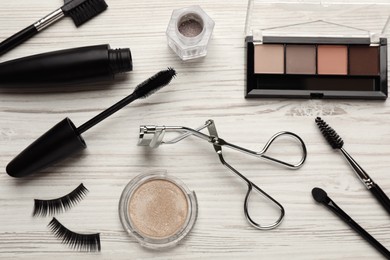 Photo of Flat lay composition with eyelash curler, makeup products and accessories on white wooden table