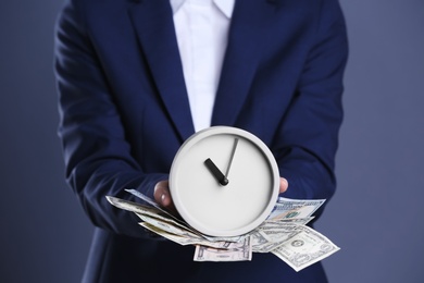 Photo of Businesswoman holding alarm clock and cash on color background. Time is money concept