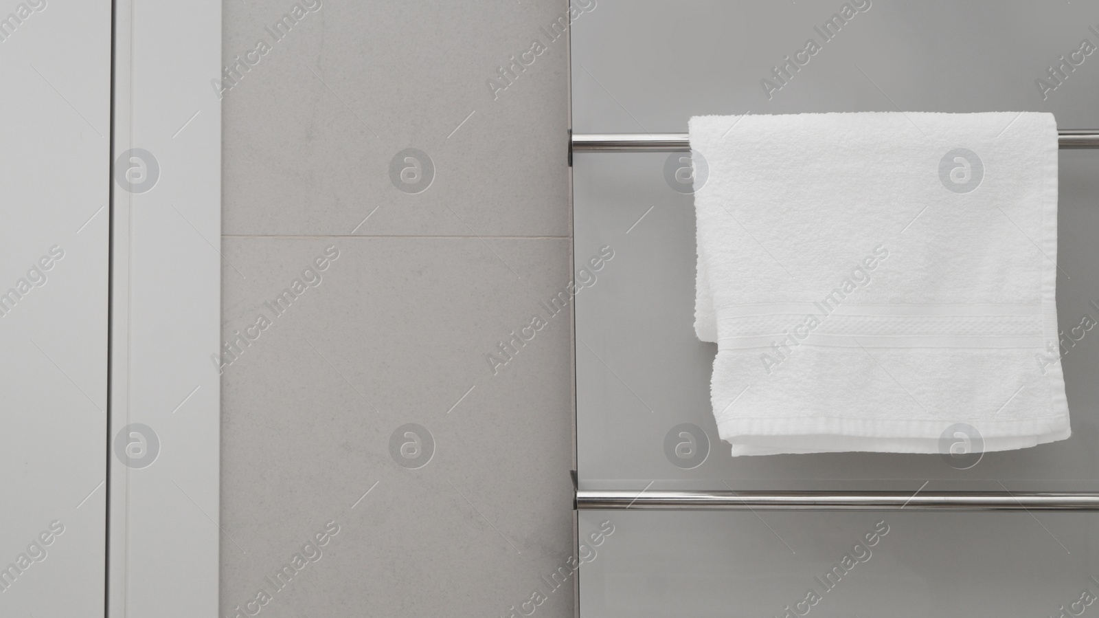Photo of Clean towel on heated rail in bathroom, space for text