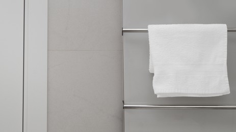 Clean towel on heated rail in bathroom, space for text