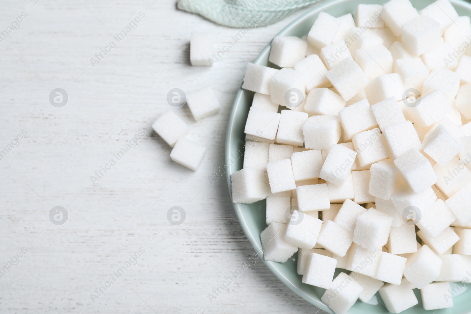 Photo of Refined sugar cubes on white wooden table, flat lay