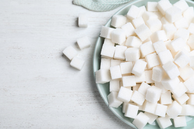 Refined sugar cubes on white wooden table, flat lay