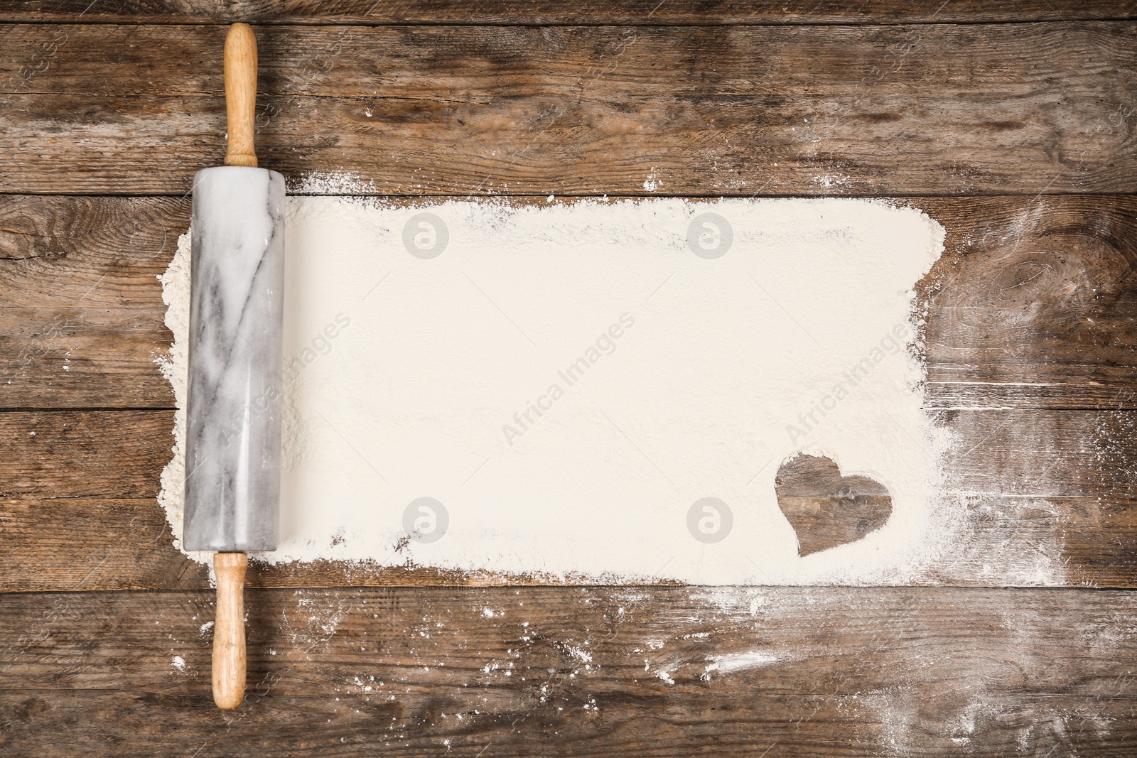 Photo of Flour and rolling pin on wooden table, flat lay