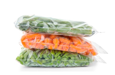 Plastic bags with frozen vegetables on white background