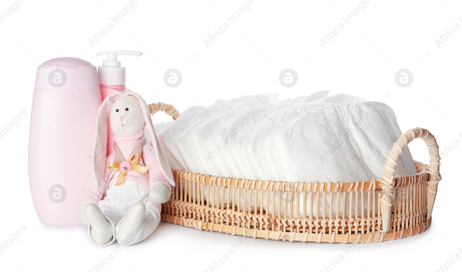 Photo of Wicker tray with disposable diapers, toy bunny and toiletries on white background