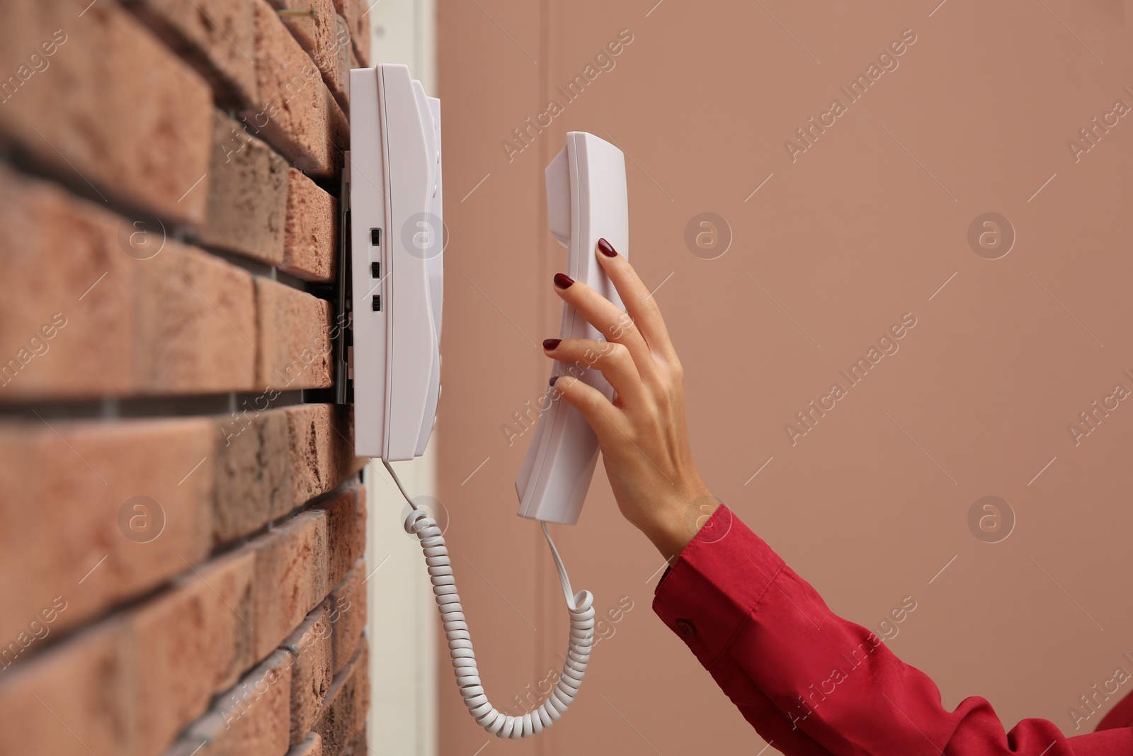 Photo of African-American woman answering intercom call indoors, closeup