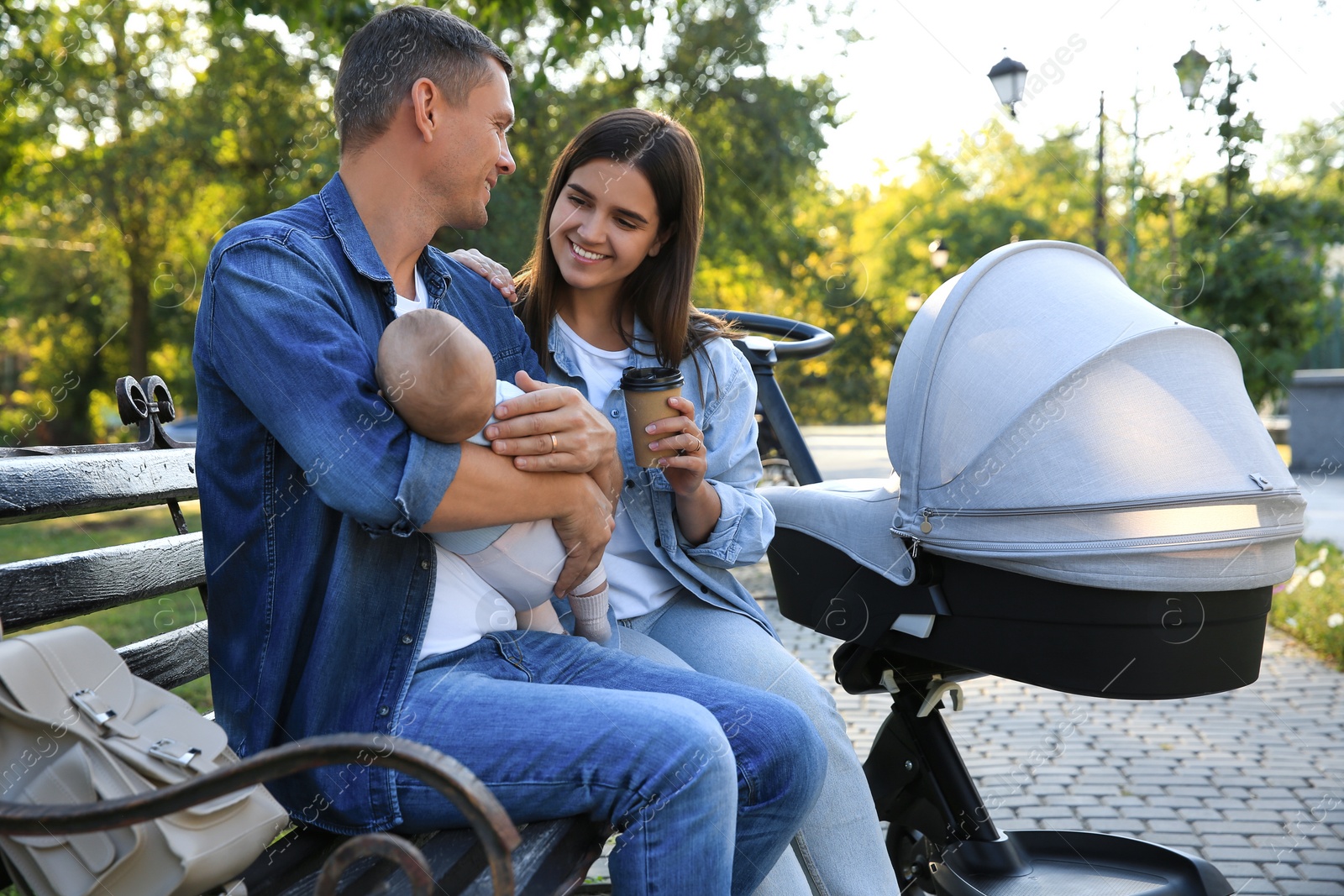 Photo of Happy parents with their baby on bench in park