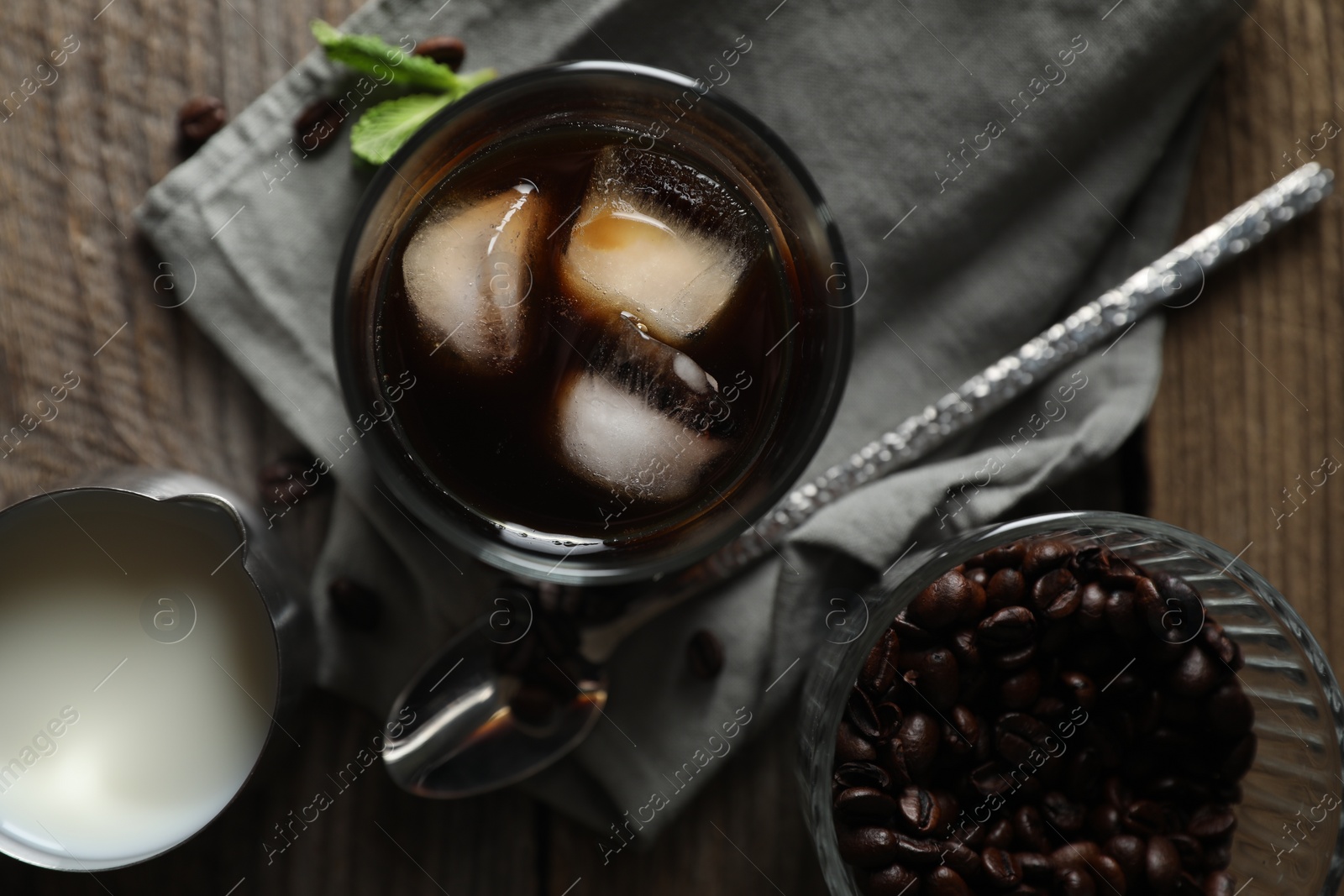 Photo of Delicious iced coffee, mint, milk and beans on wooden table, flat lay