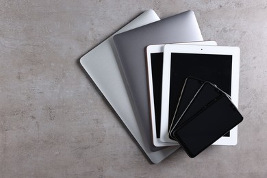 Photo of Many different modern gadgets on grey table, top view. Space for text