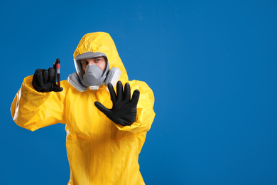 Photo of Man in chemical protective suit holding test tube of blood sample on blue background, space for text. Virus research
