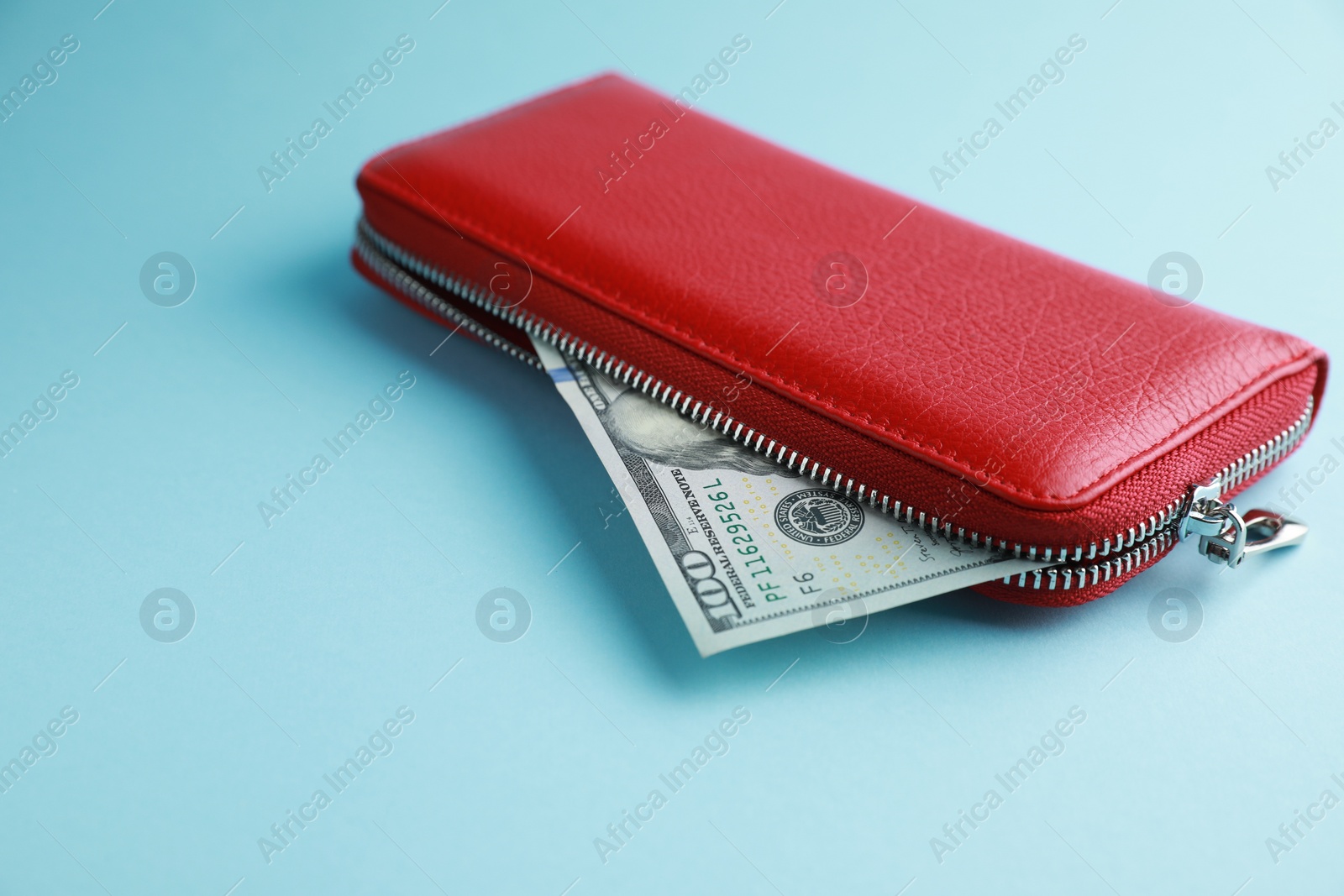 Photo of One stylish leather purse with money on light blue background. Space for text