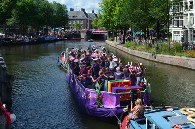AMSTERDAM, NETHERLANDS - AUGUST 06, 2022: Many people in boats at LGBT pride parade on river