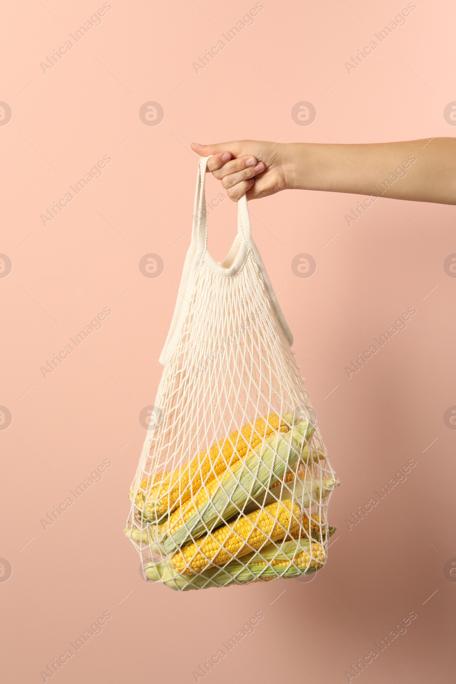 Photo of Woman with bag of corn cobs on pink background, closeup