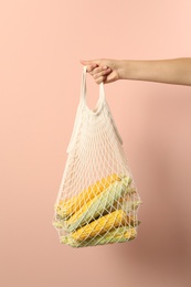 Photo of Woman with bag of corn cobs on pink background, closeup