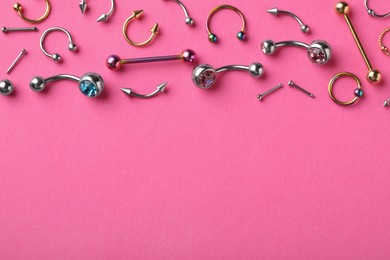 Photo of Stylish piercing jewelry on pink background, flat lay. Space for text