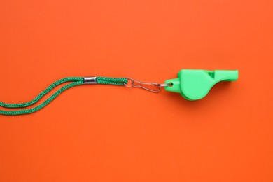 Photo of One green whistle with cord on orange background, top view