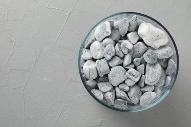 Presentation for product. Glass container with stones on grey textured background, top view. Space for text