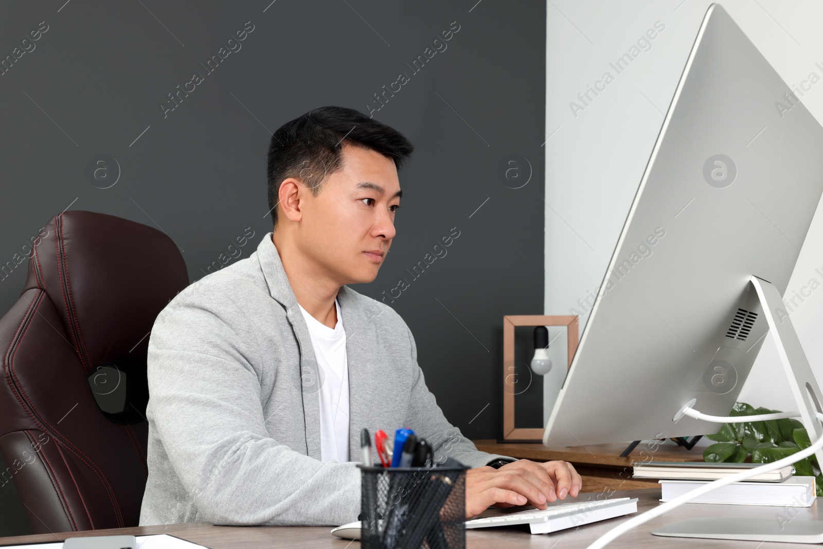 Photo of Boss working on computer at wooden table in his modern office