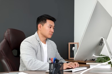 Boss working on computer at wooden table in his modern office