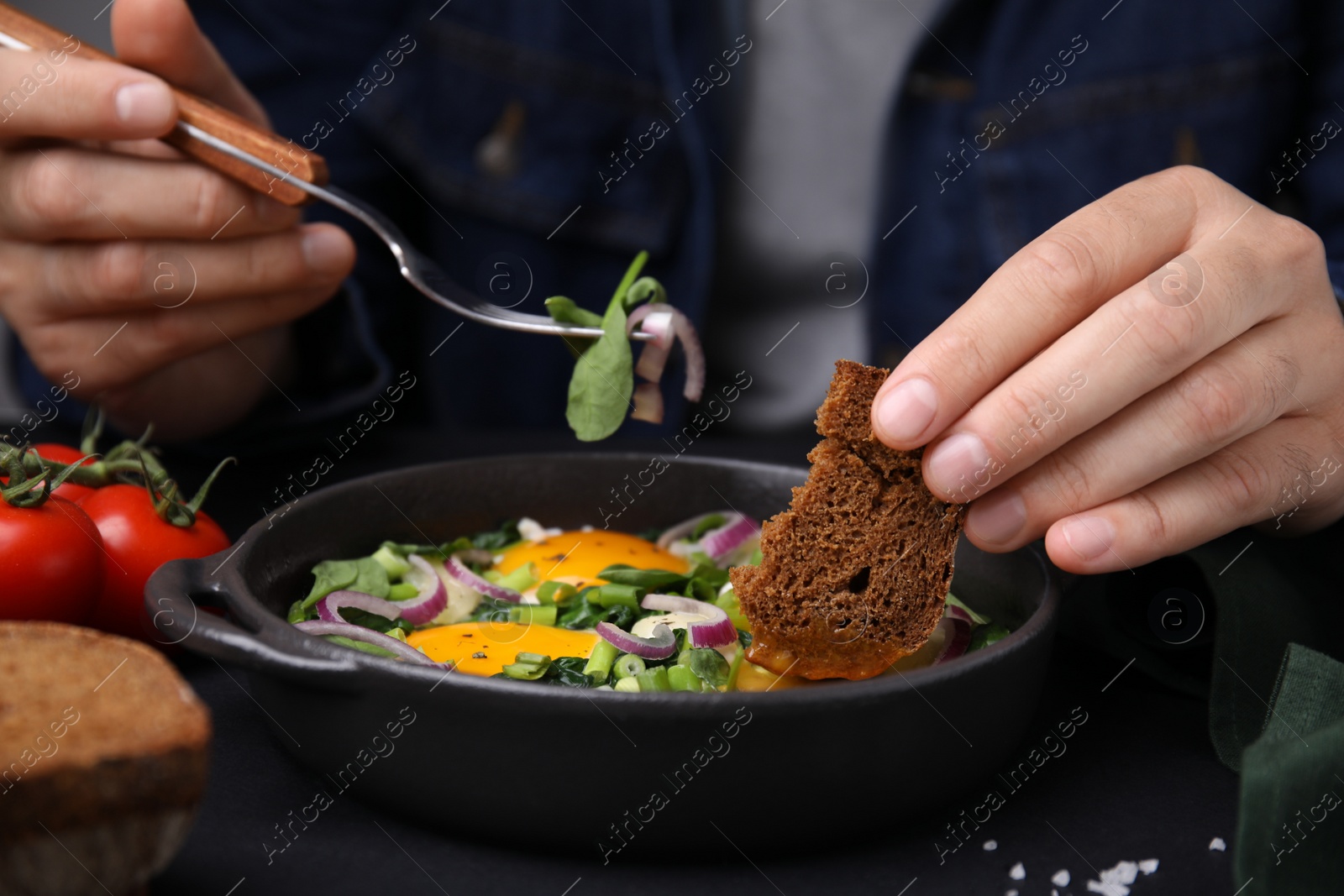 Photo of Woman dipping piece of bread into egg yolk, closeup. Eating tasty Shakshuka