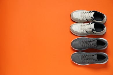 Different stylish sport shoes on orange background, flat lay. Space for text