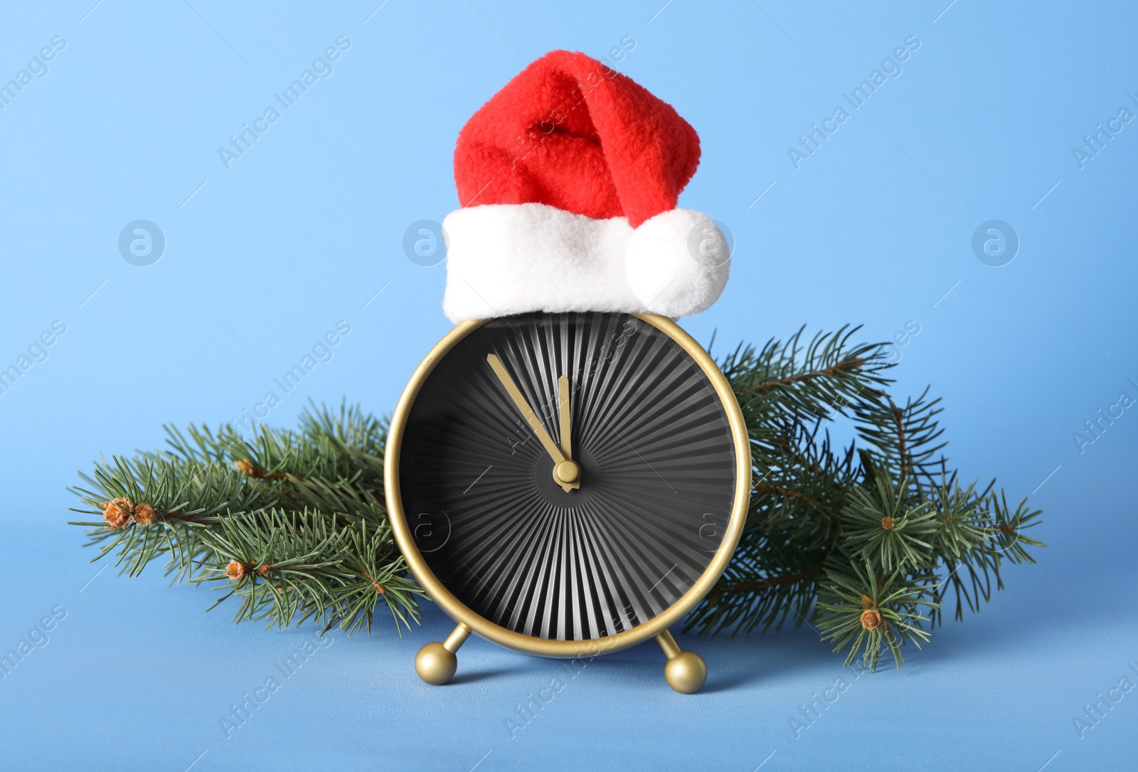 Photo of Stylish clock with Christmas decor on light blue background. New Year countdown