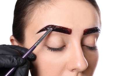 Photo of Beautician applying tint during eyebrows correction procedure on white background, closeup