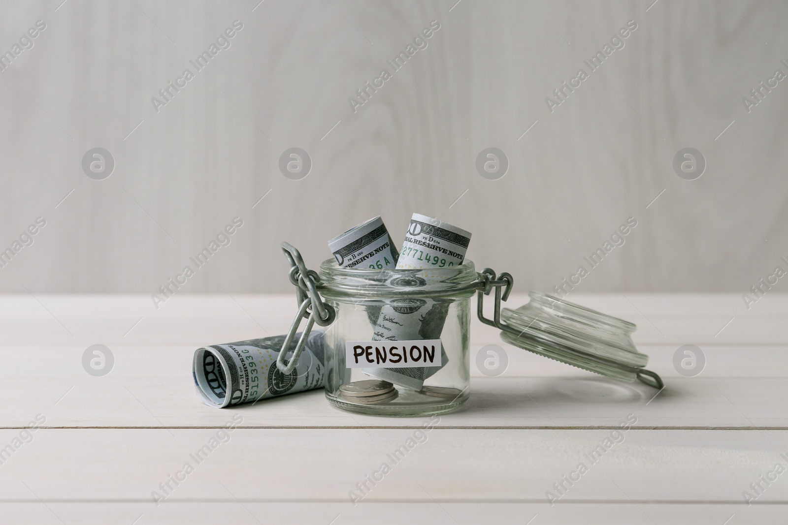 Photo of Glass jar with word Pension, coins and dollar banknotes on white wooden table, space for text