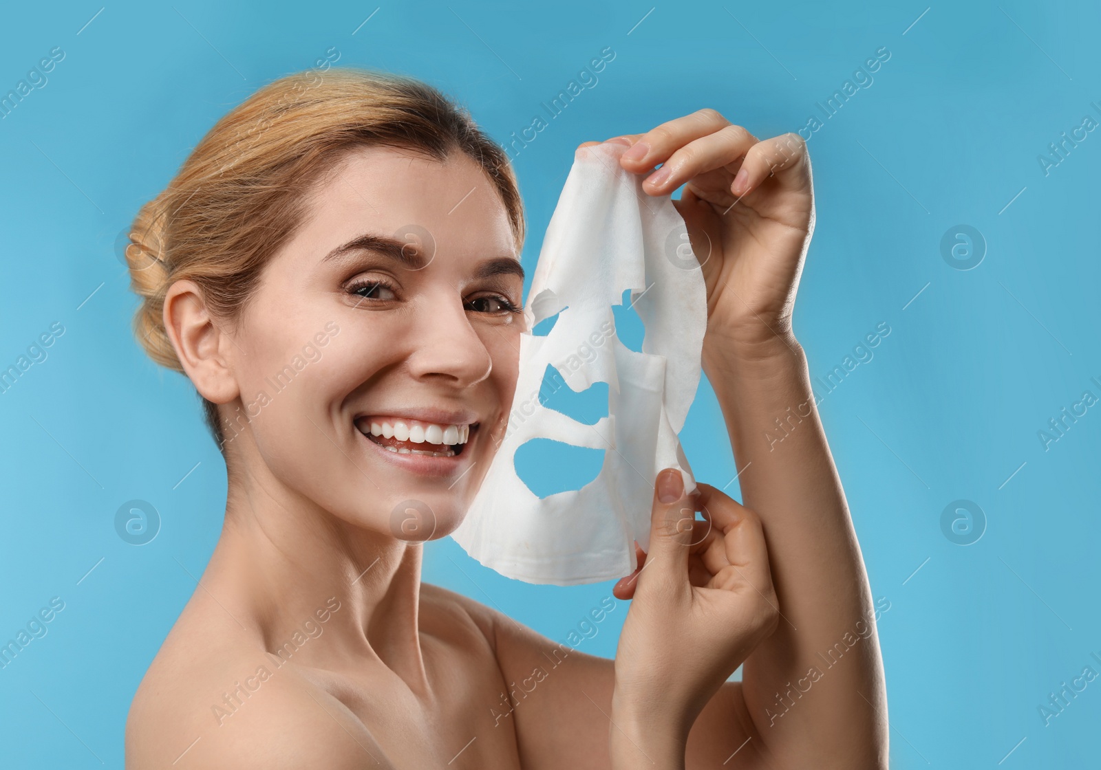 Photo of Beautiful woman with cotton facial mask sheet against color background