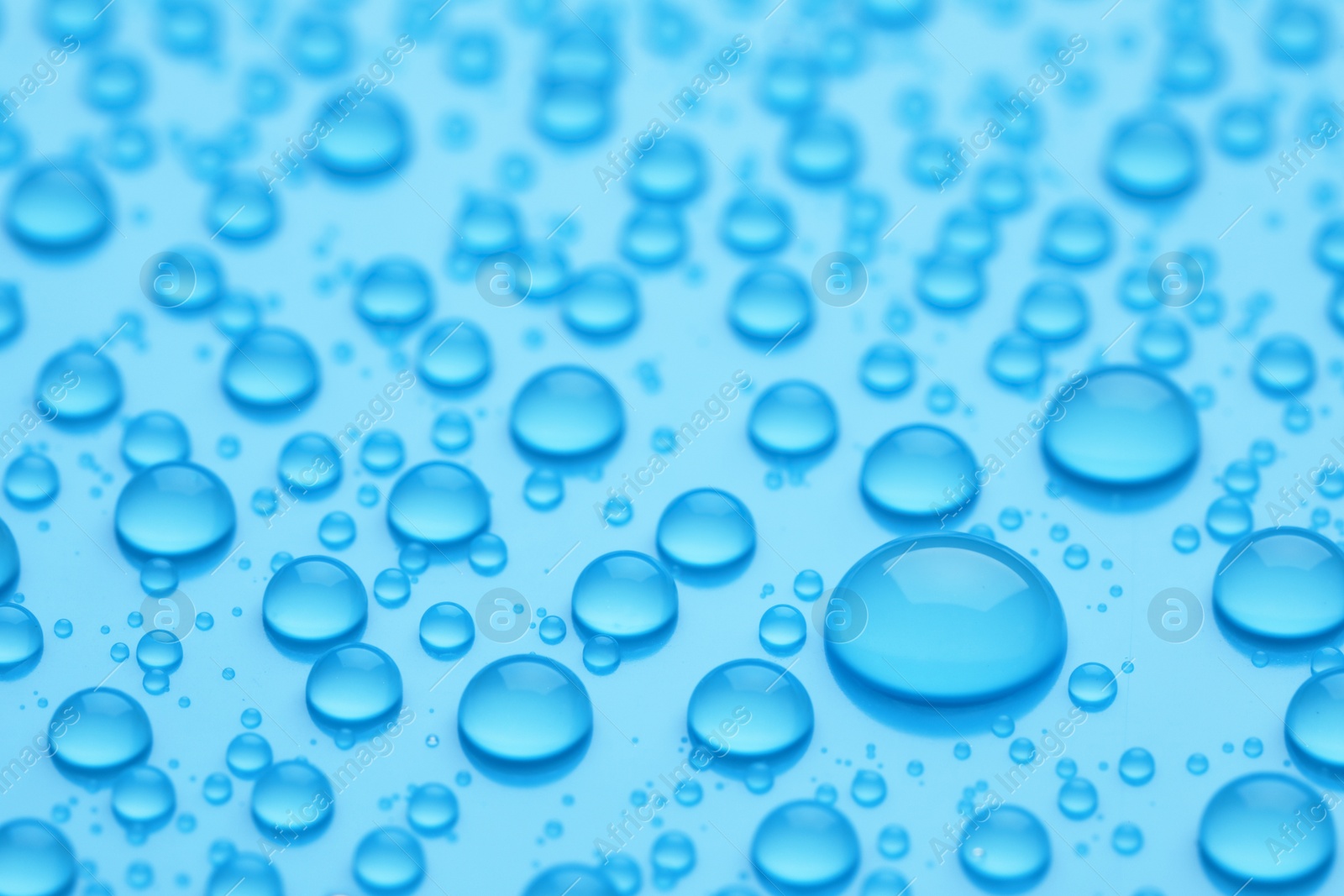 Photo of Water drops on light blue background, closeup view