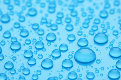 Water drops on light blue background, closeup view