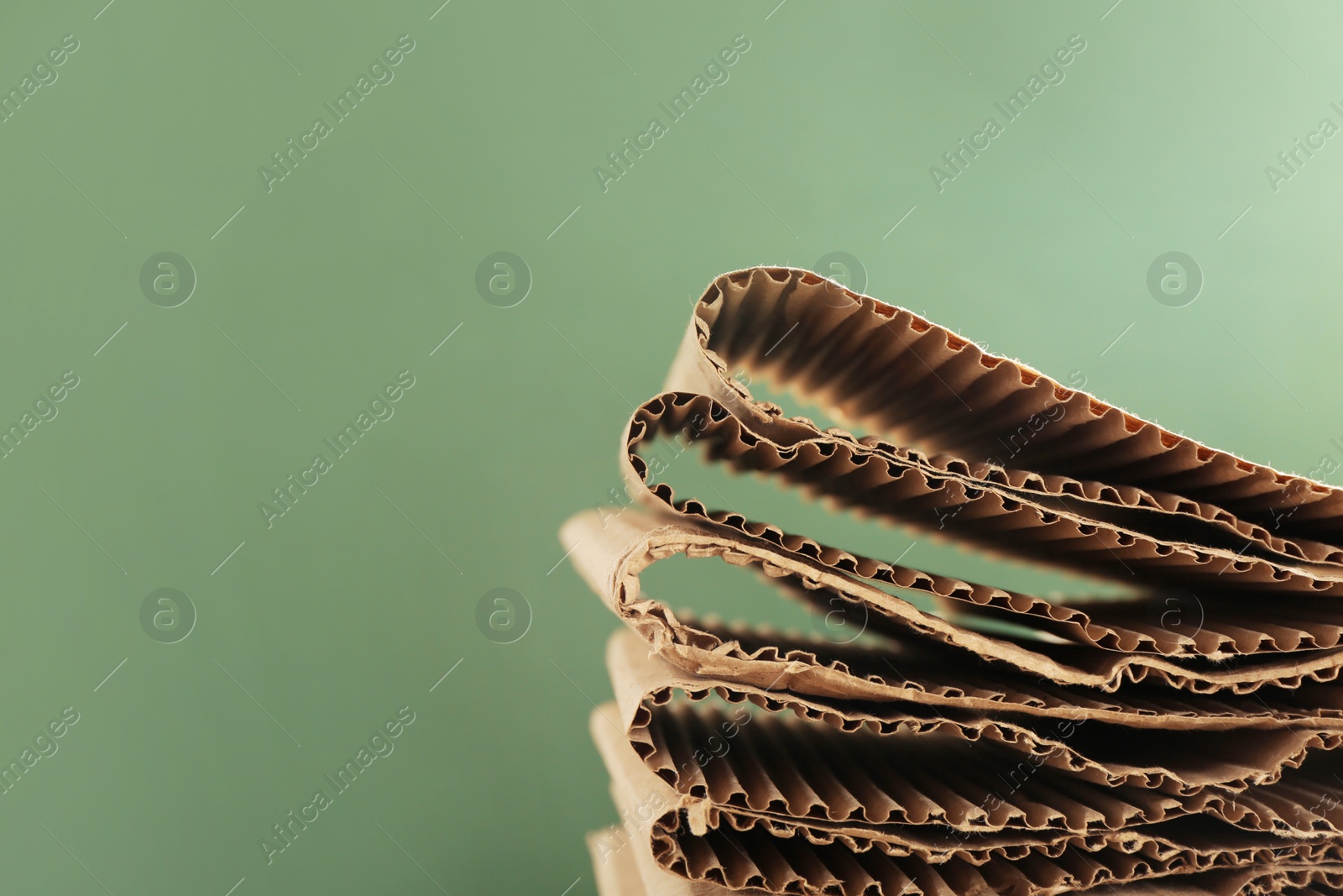 Photo of Stack of cardboard on green background, closeup with space for text. Recycling concept