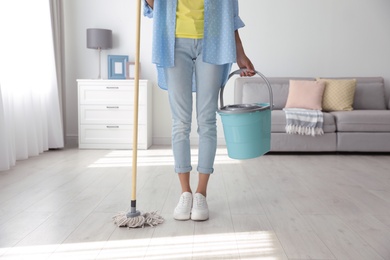 Photo of Woman with mop and bucket at home, closeup. Cleaning supplies