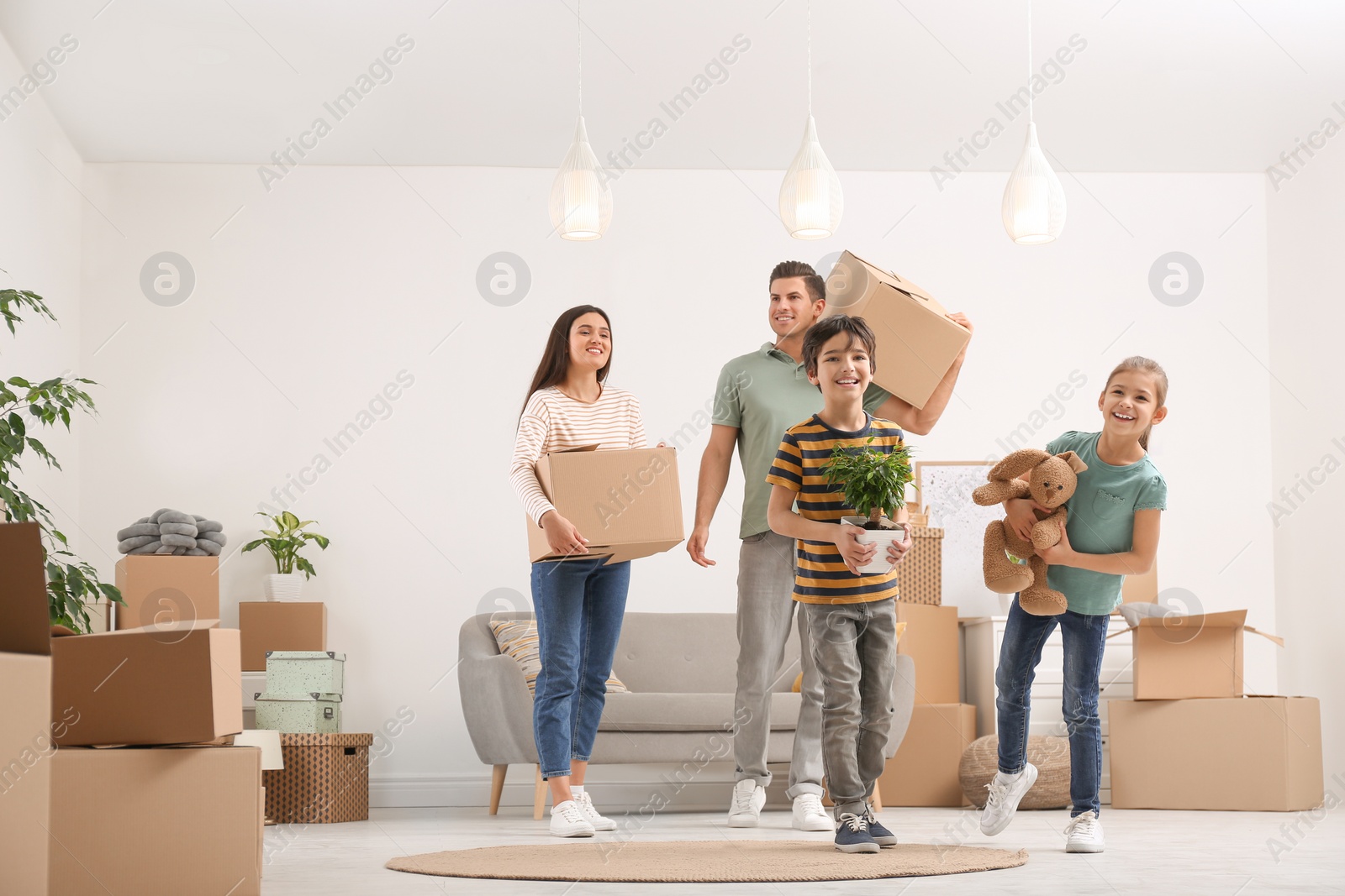 Photo of Happy family in room with cardboard boxes on moving day